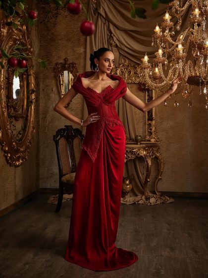 Crimson confidence, sculpted to stun. This full-length view shows the structured, embellished corset meeting the fluid drapes of the gown's skirt, a perfect fusion of tailoring and flow.