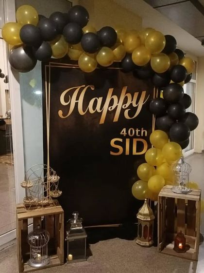 A classic black and gold 40th birthday setup with a custom banner and rustic crate props.