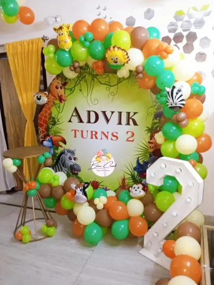 A detailed jungle-themed second birthday with a custom backdrop, organic balloon garland, and a light-up number '2'.