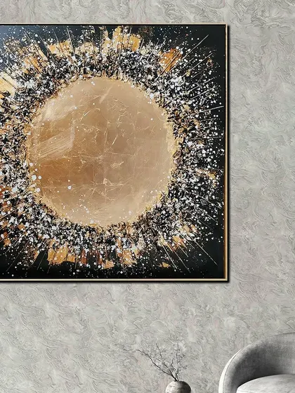This 'Cosmic Burst Opulence' wall painting is a square canvas featuring an explosive abstract design. The central golden circle is surrounded by a burst of black, white, and gold, adding a touch of cosmic wonder to your decor.
