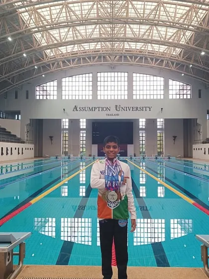 This is the result of dedication. Here is our swimmer, Bryce, proudly displaying his gold, silver, and bronze medals at the Asian Open Schools Invitational Swimming Championship in Thailand. This image captures the proud moment of achievement at a world-class swimming facility, a goal we help our competitive swimmers reach.
