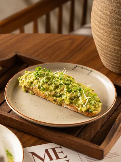 A mashed avocado toast with microgreens. This version highlights a different texture and presentation style.