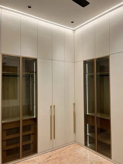 This floor-to-ceiling wardrobe in an Ambala master bedroom combines closed storage with glass-fronted sections. The integrated lighting inside the glass units allows for displaying accessories while keeping them organized.