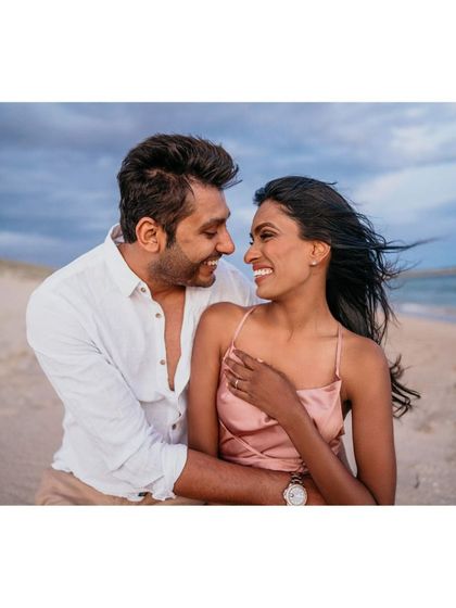 An intimate and windswept moment from a beach pre-wedding session. The natural elements, like the wind and the sea, add a raw and beautiful energy to the photos.
