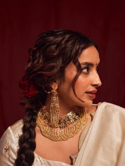 A side-profile beauty shot, showcasing the elaborate earrings and the delicate details of the makeup and hair. This angle provides a different, elegant perspective on the traditional look.