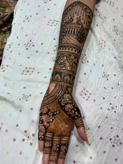 A complete view of a bridal arm design, combining peacock figures, traditional pot symbols, and delicate floral patterns on the hand.