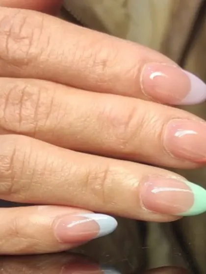 Another view of the pastel rainbow French tips, showcasing the gentle colors on almond-shaped nails.
