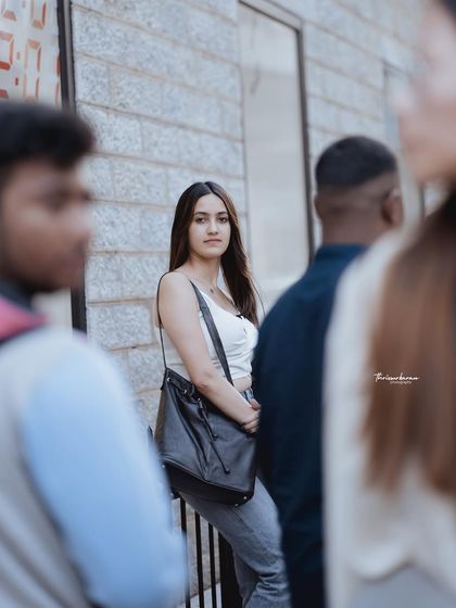 This shot uses foreground and background elements to create a sense of depth and place the subject within a busy street scene. It gives the portrait a fly-on-the-wall, authentic feel.