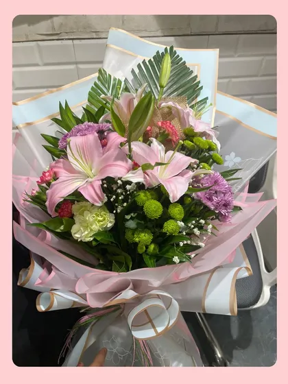 Some fresh blooms to brighten your day. This hand-tied bouquet features pink lilies, purple carnations, and green chrysanthemums, all secured with love and a beautiful wrap.