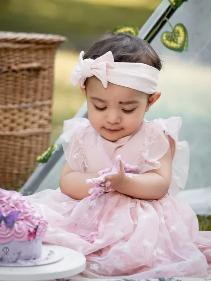 A sweet moment as the birthday girl looks down at her hands covered in pink frosting. These toddler photoshoots are all about capturing their genuine curiosity and delight.