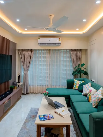 This shot captures the entire living room layout, from the sofa to the TV unit, under warm, layered lighting.