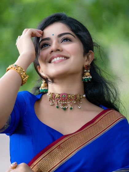 The joy in this image is infectious. The model's upward glance and bright smile, combined with the classic blue saree, create a portrait that feels both candid and beautifully composed.