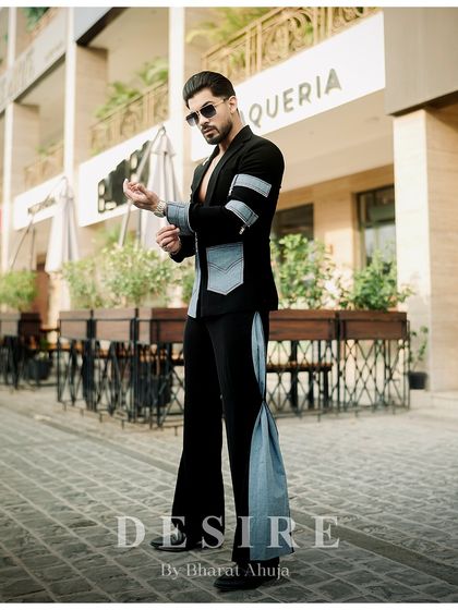 Adjusting the cuff on the black and denim fusion jacket. This shot highlights the denim armband details and the overall edgy aesthetic.