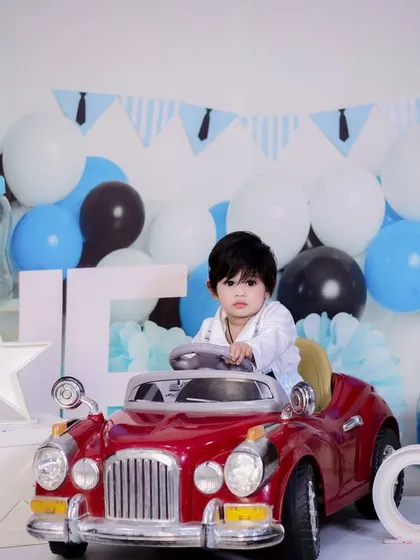 A stylish shot of the one-year-old in his car, looking like a true gentleman. The blue and black decor adds a classic touch.