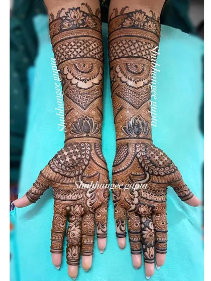 This is a classic example of a full coverage engagement mehndi design. The pattern uses a mix of geometric checks, delicate lotus flowers, and traditional motifs for a rich and balanced look.