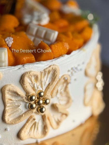 A close-up of the delicate, hand-piped floral details on the side of the mango cake.