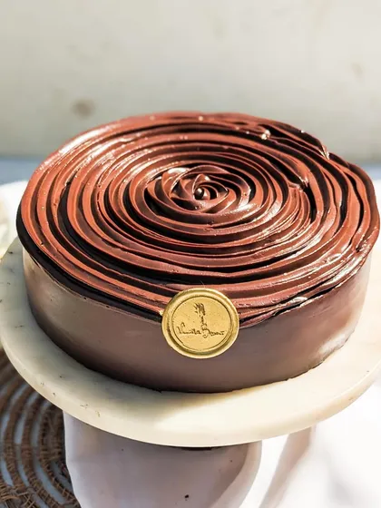 Our Belgian Dark Chocolate cake on a stand, ready to be the centerpiece of your celebration. It's simple, elegant, and incredibly decadent.