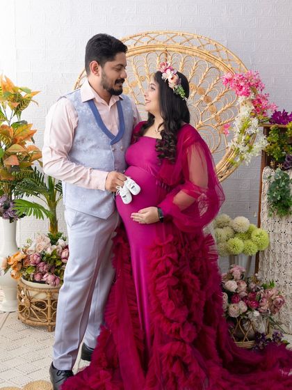 The couple shares a loving glance while holding the baby shoes. This candid interaction adds a layer of warmth and personality to the classic pose.