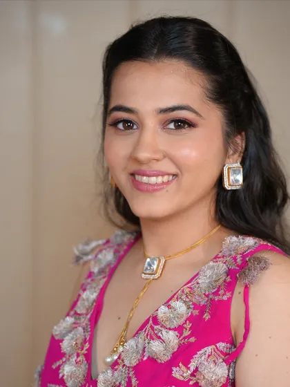 A soft, romantic look perfect for a wedding guest or bridesmaid. The makeup features pretty pink tones on the eyes and lips, paired with a simple half-up hairstyle.