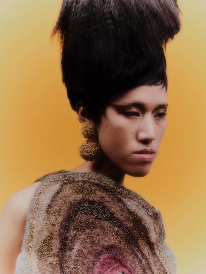 A three-quarter profile shot that shows how the earrings interact with the model's jawline and the unique texture of the garment.