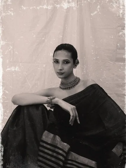 A black and white portrait with a vintage, film-like texture. The image has a timeless, classic feel, focusing on the model's expression and the traditional silver jewelry.