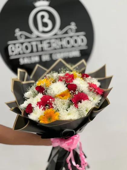 A custom bouquet made for a local salon, featuring a mix of red, yellow, and white gerberas and chrysanthemums. The arrangement is wrapped in stylish black paper with a pink ribbon.