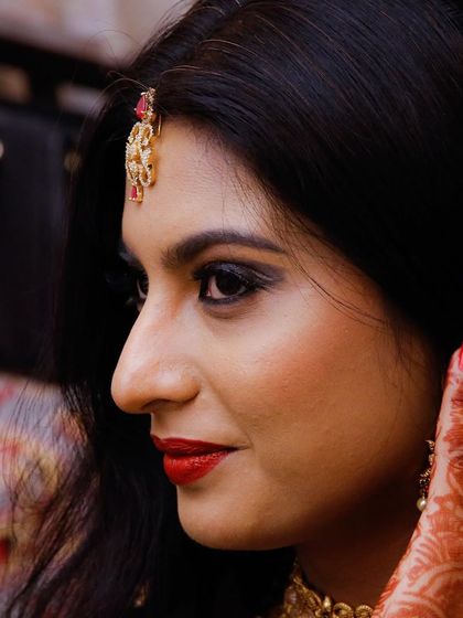A candid side-profile of a bride, capturing her thoughtful expression and the intricate details of her makeup and henna.