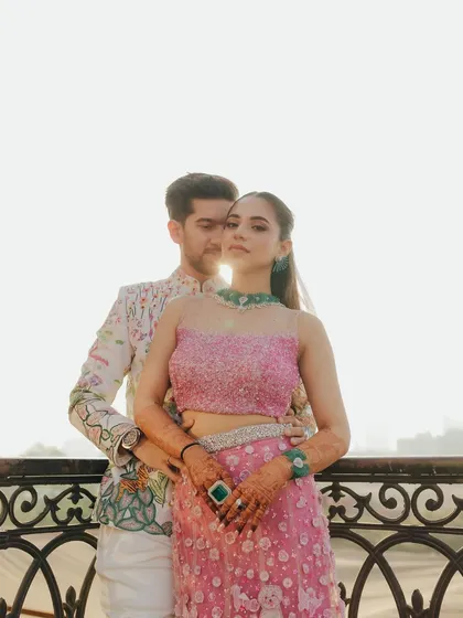 A stylish portrait against an ornate railing. The backlighting from the sun creates a beautiful glow, highlighting the couple's elegant silhouettes and confident poses.