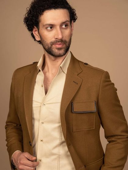 A mustard-colored suit with unique leather-trimmed pocket details. This is an example of how I can incorporate unconventional details for a modern, travel-friendly look.