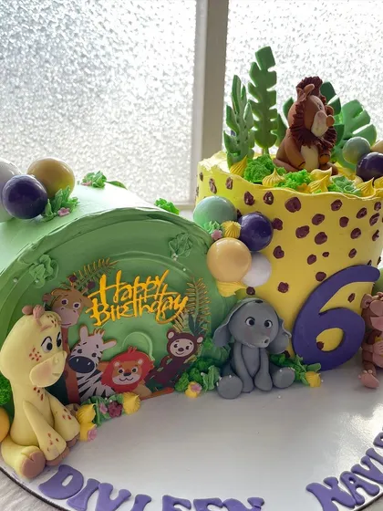 This jungle cake was designed for twins, with a unique half-and-half structure. It's packed with cute, handmade animals like a giraffe, zebra, and lion peeking out of the foliage.
