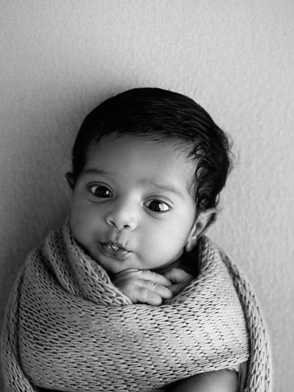 A beautiful black and white portrait of a newborn wrapped snugly, their bright, curious eyes making a connection with the camera. Sometimes the most powerful images are the simplest.