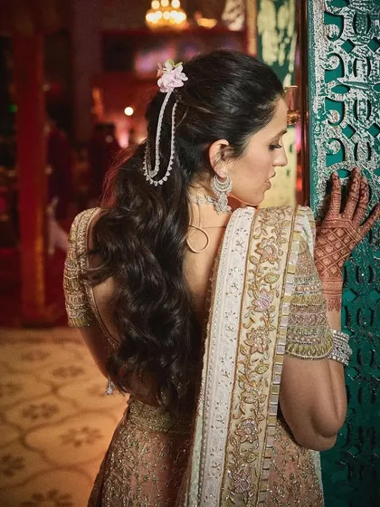 A stunning back view of the peach Abu Jani Sandeep Khosla lehenga, showcasing the detailed blouse, low back, and beautiful hair accessory.