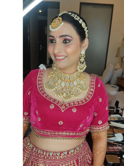 A happy client getting her final touches done. She is wearing a pink velvet blouse with a heavy kundan necklace.