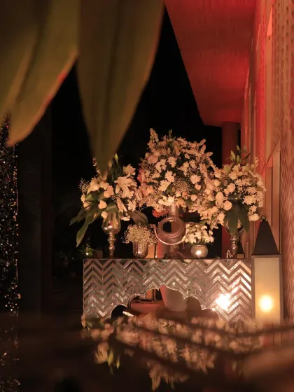 Details make the design. This mirrored console table with large white floral arrangements added a touch of elegance and reflected the warm, ambient lighting of the Sangeet venue.