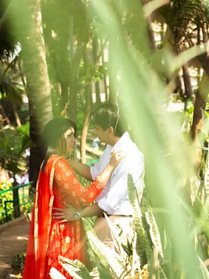 An artistic shot taken through leaves, creating a natural frame around the couple. This technique adds depth and a sense of intimacy, as if we are peeking into a private, romantic moment.