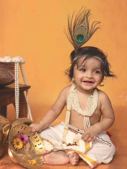 Another joyful portrait of our little Krishna. The props, including the flute and decorative pot, add authentic touches to the scene.