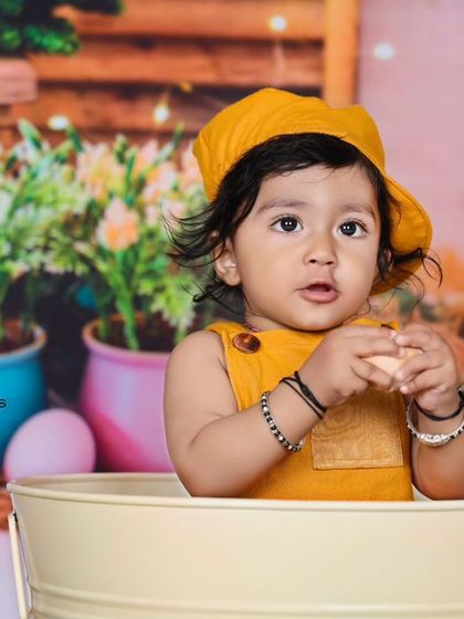 A close-up of the baby in the bunny-themed setup, holding a small egg. The soft lighting and detailed props create a sweet and festive atmosphere.