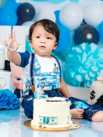 A baby boy points a frosting-covered finger during his "Boss Baby" cake smash. It's a fun, interactive shot that shows his personality.