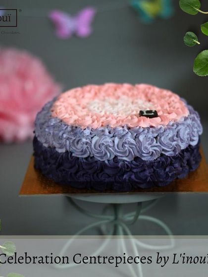 We create centrepieces that taste as good as they look. This custom-designed celebration cake features delicate buttercream rosettes, showcasing our ability to tailor our creations for your special events.