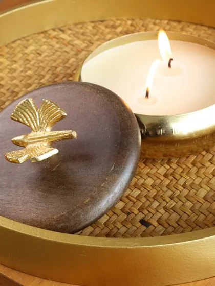 Our two-wick scented candle in a brass bowl with a wooden lid, adorned with a golden bird. This piece combines natural materials with metallic accents for a rustic-luxe feel.