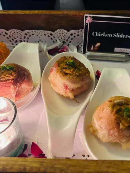 Chicken Sliders served on elegant porcelain spoons. This bite-sized appetizer is perfect for guests to enjoy easily while socializing at an event.