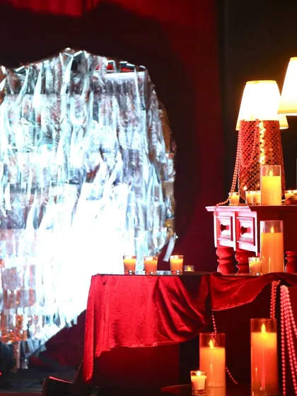 We mix different textures to create visual interest. Here, a crinkled silver foil backdrop contrasts with soft red velvet and the warm glow of candles, adding depth to the decor.