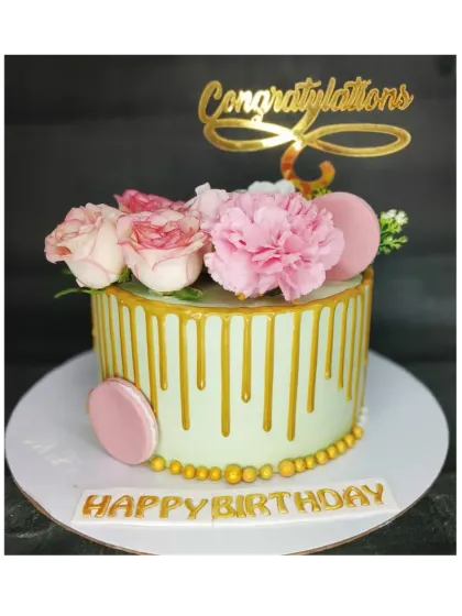 A beautiful congratulations cake with a golden drip. This chocolate truffle cake is topped with fresh flowers and macarons for an elegant celebration.