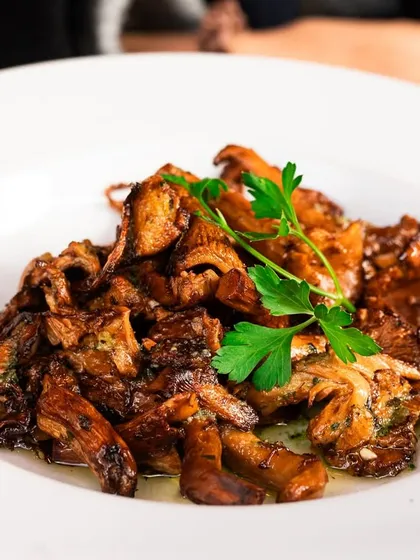 A beautiful plate of sautéed chanterelle mushrooms. The focus is on the golden color and texture of the wild mushrooms.