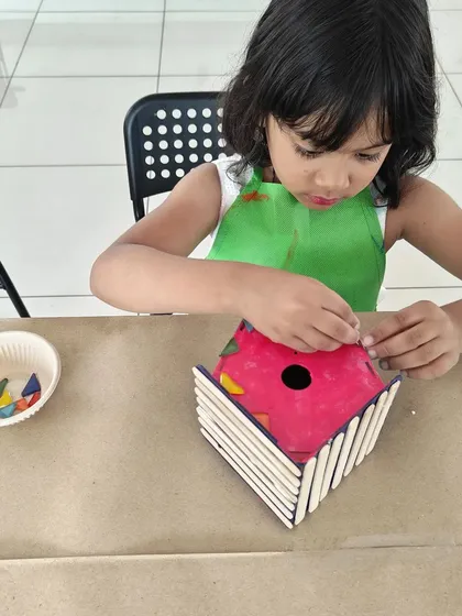 I love seeing the concentration on their faces! Here, a young artist is carefully assembling her own colorful birdhouse, a perfect take-home creation.