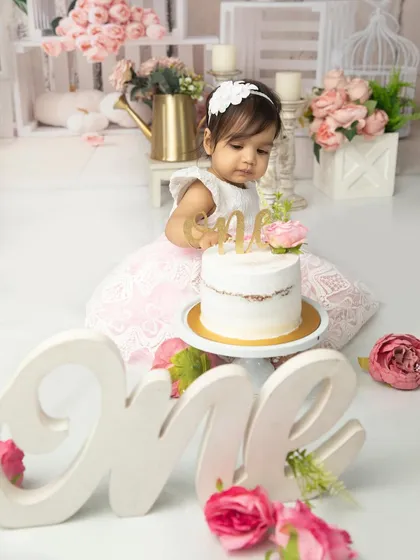 A quiet moment of admiration for the birthday cake. The large "one" sign in the foreground adds a beautiful touch to this first birthday portrait.