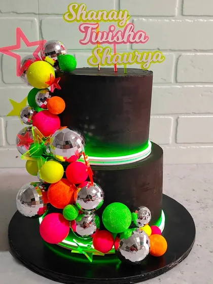 A full view of the incredible neon party cake. The glowing green lights make the bright colors and disco balls pop, creating an amazing centerpiece for a glow-in-the-dark party.