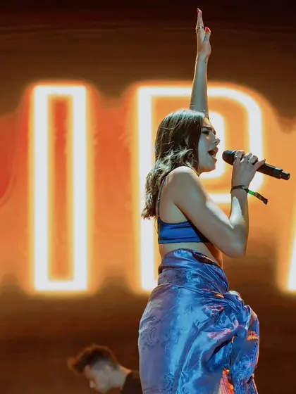 Capturing international pop star Dua Lipa live on stage. This shot highlights her powerful stage presence against the bold, illuminated backdrop of her name.