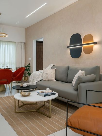 A complete view of the living and dining area in the Soul Spring mock-up unit. The space is unified by a warm, textured wall finish, while bold red dining chairs provide a vibrant contrast to the otherwise neutral and calming palette.