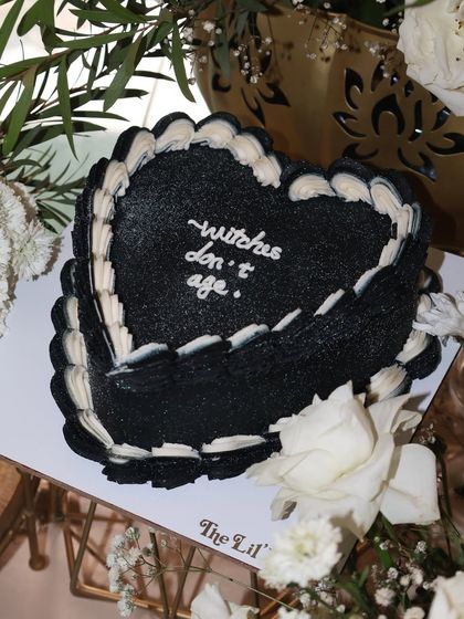 Casting a spell for eternal youth, one bite at a time. This black heart-shaped cake with the quote "witches don't age" is perfect for a spooky, chic birthday.